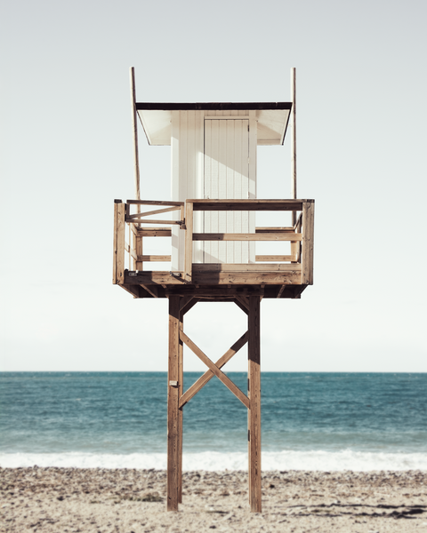 Wooden lifeguard tower on a beach with ocean in the background
